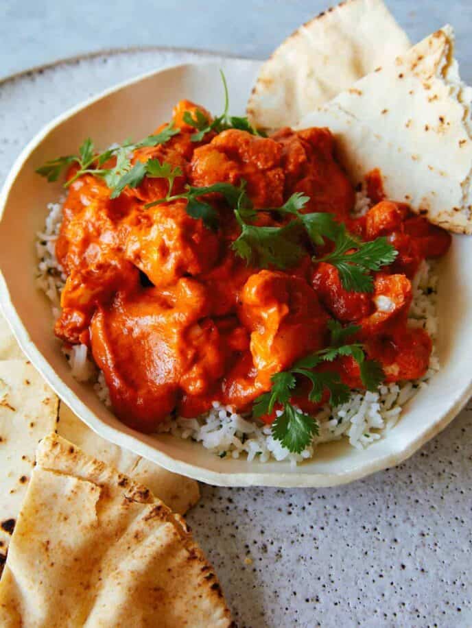 Indian butter cauliflower over white rice in a bowl with pita bread.