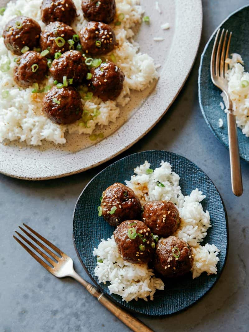 Korean BBQ meatballs on a platter served onto two plates next to it.