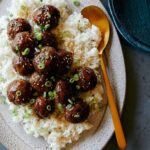 Korean BBQ meatballs over white rice with a spoon.