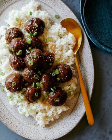 Korean BBQ meatballs over white rice with a spoon.
