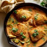 Thai red curry chicken thighs in a pan.