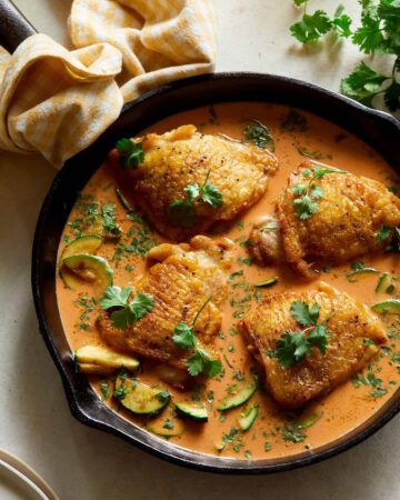 Thai red curry chicken thighs in a pan.