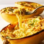 Vegan baked alfredo spaghetti squash with some squash twirled on a fork.