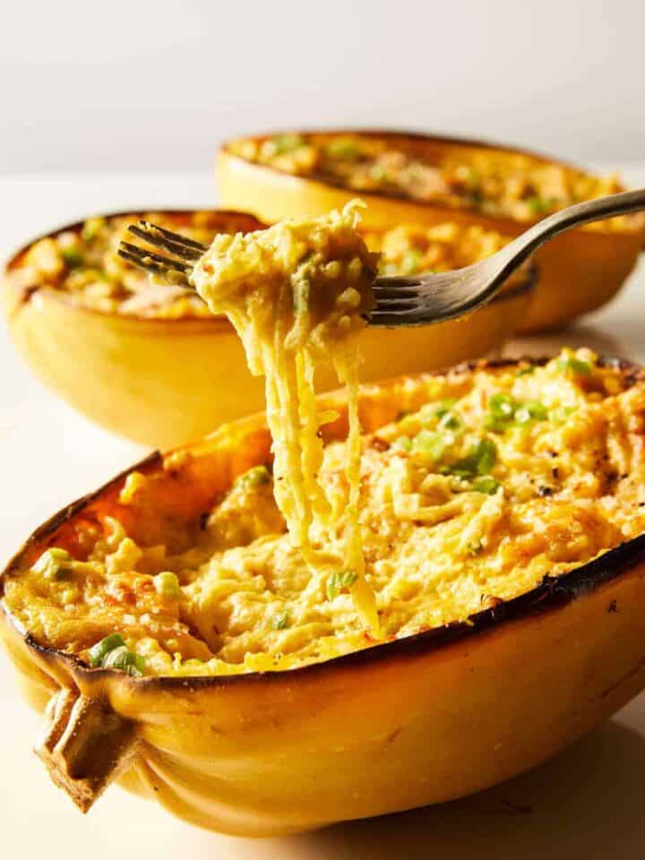 Vegan baked alfredo spaghetti squash with some squash twirled on a fork.