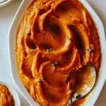 A close up of butternut squash puree in a bowl with a spoon.