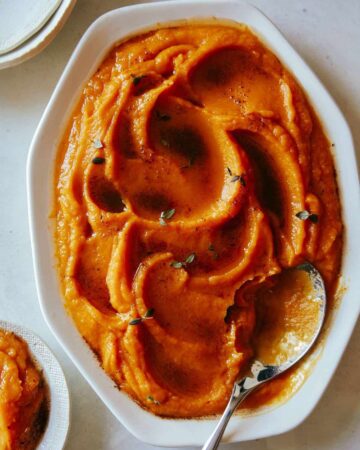 A close up of butternut squash puree in a bowl with a spoon.