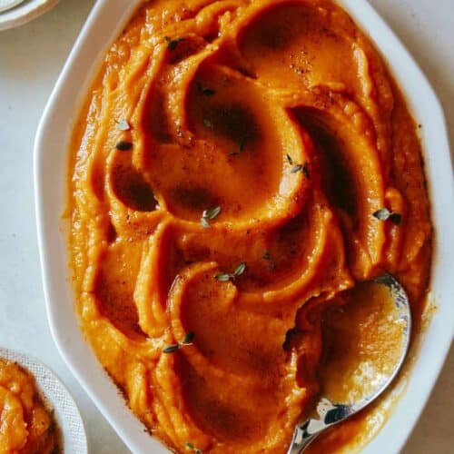 A close up of butternut squash puree in a bowl with a spoon.