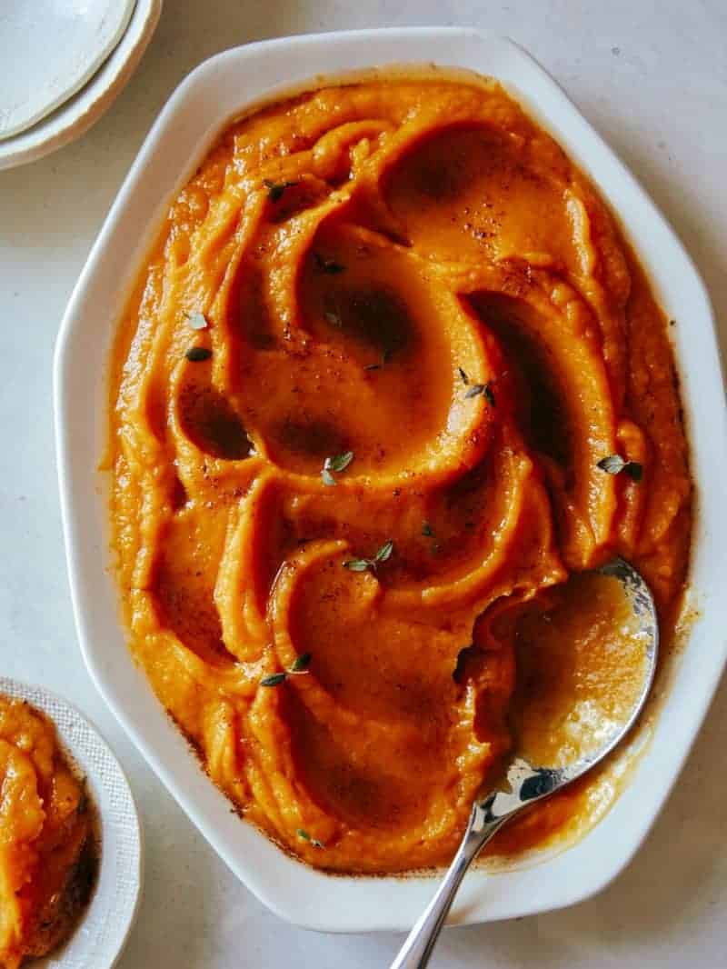 A bowl of butternut squash puree with a spoon.