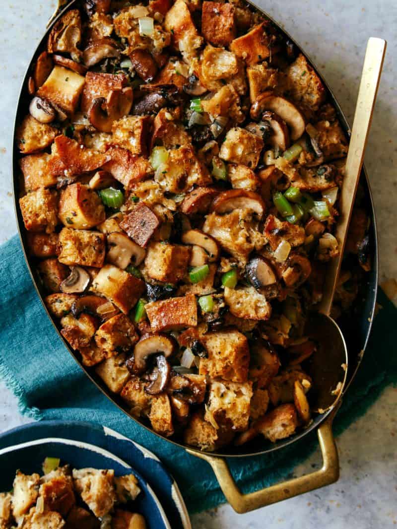 A pan of mushroom sage stuffing with a large serving spoon and linens.