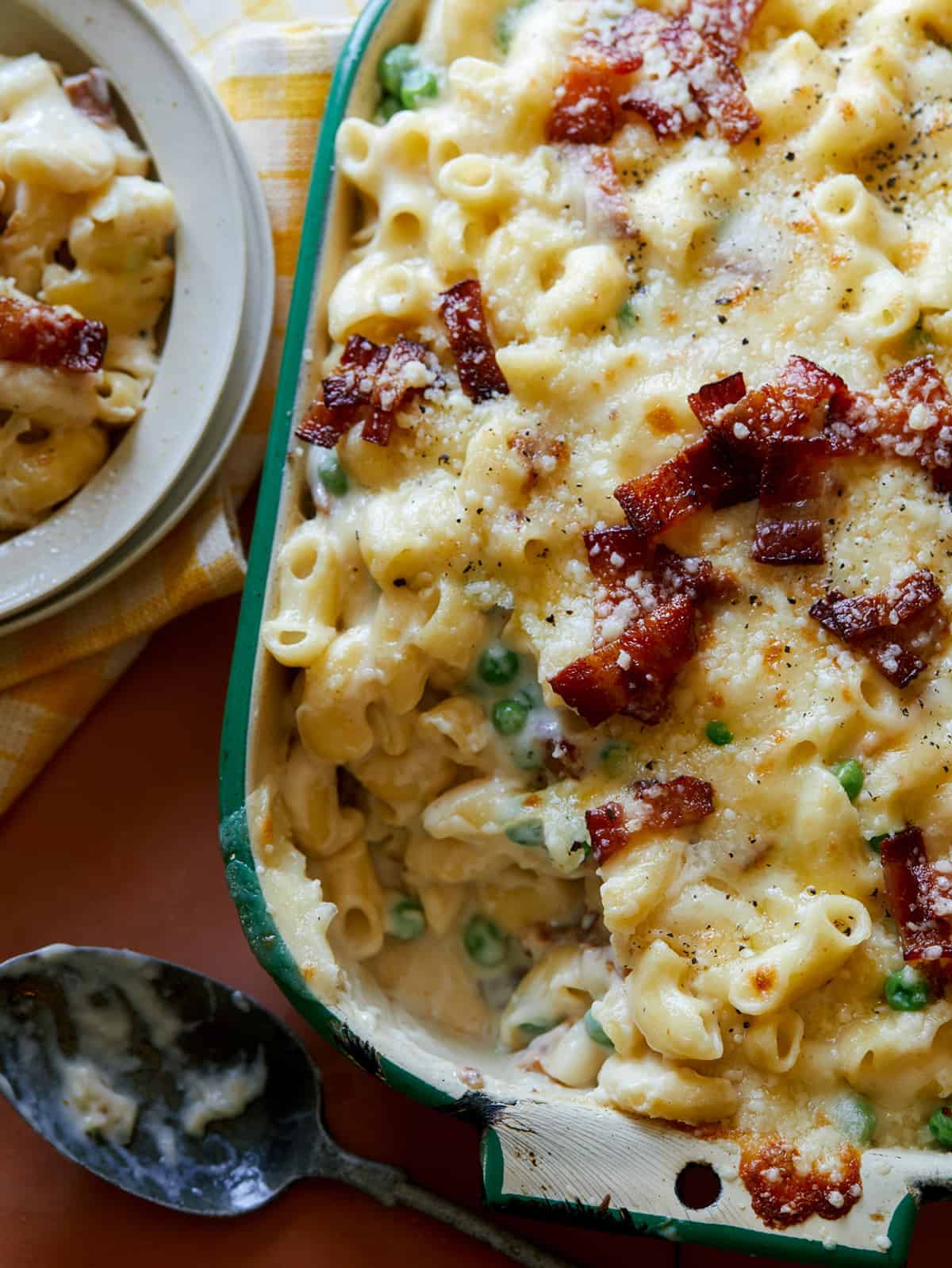 A close up of creamy baked carbonara mac and cheese.