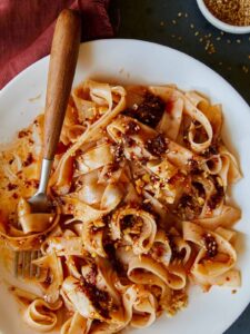 Chili oil garlic noodles on a plate twirled on a fork.