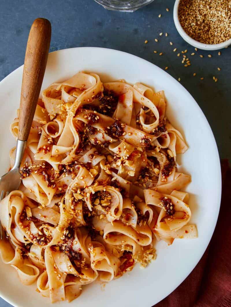 Chili oil garlic noodles on a plate with a fork next to it.