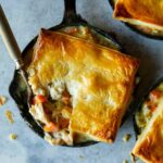 Chicken pot pies in individual skillets with a fork.
