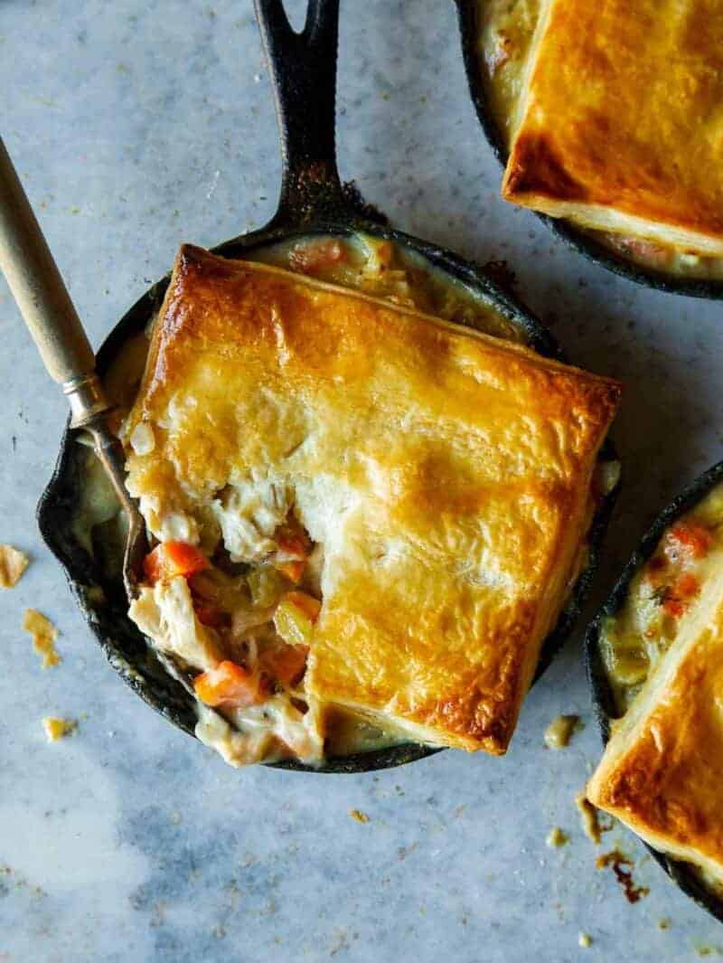 Chicken pot pies in individual skillets with a fork.