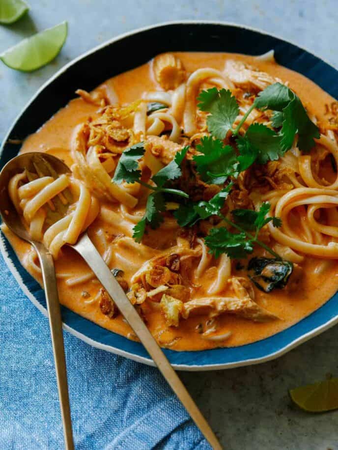 Bowl of spicy thai red curry soup with a spoon and fork.