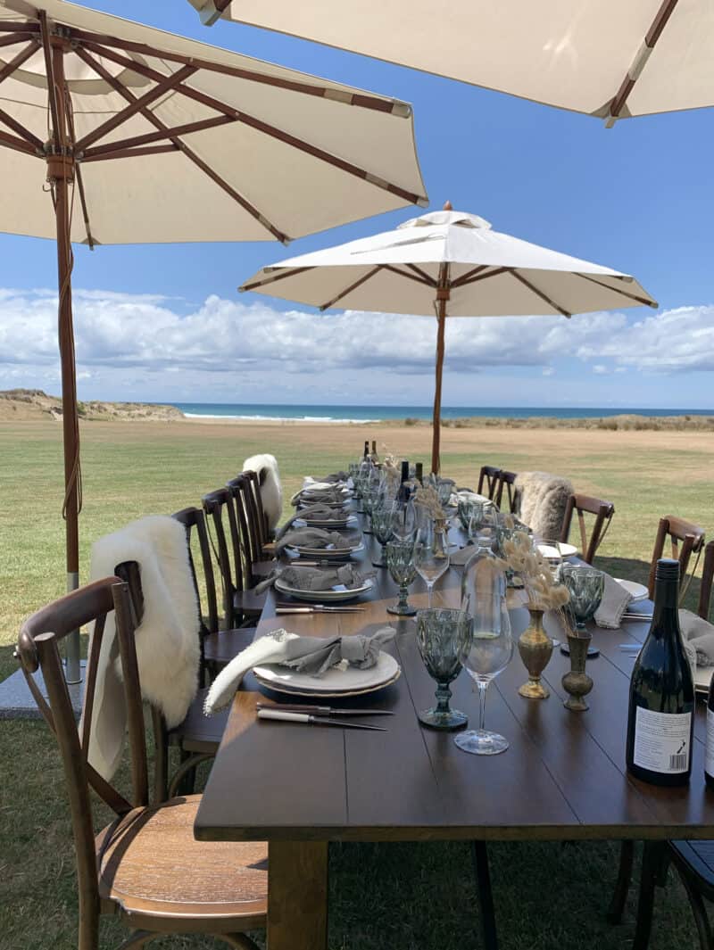 Set table for lunch party outside looking over green fields and ocean.