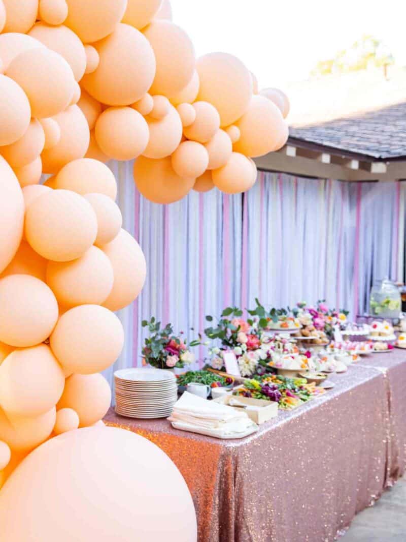 Balloon garland surrounds a table of food.