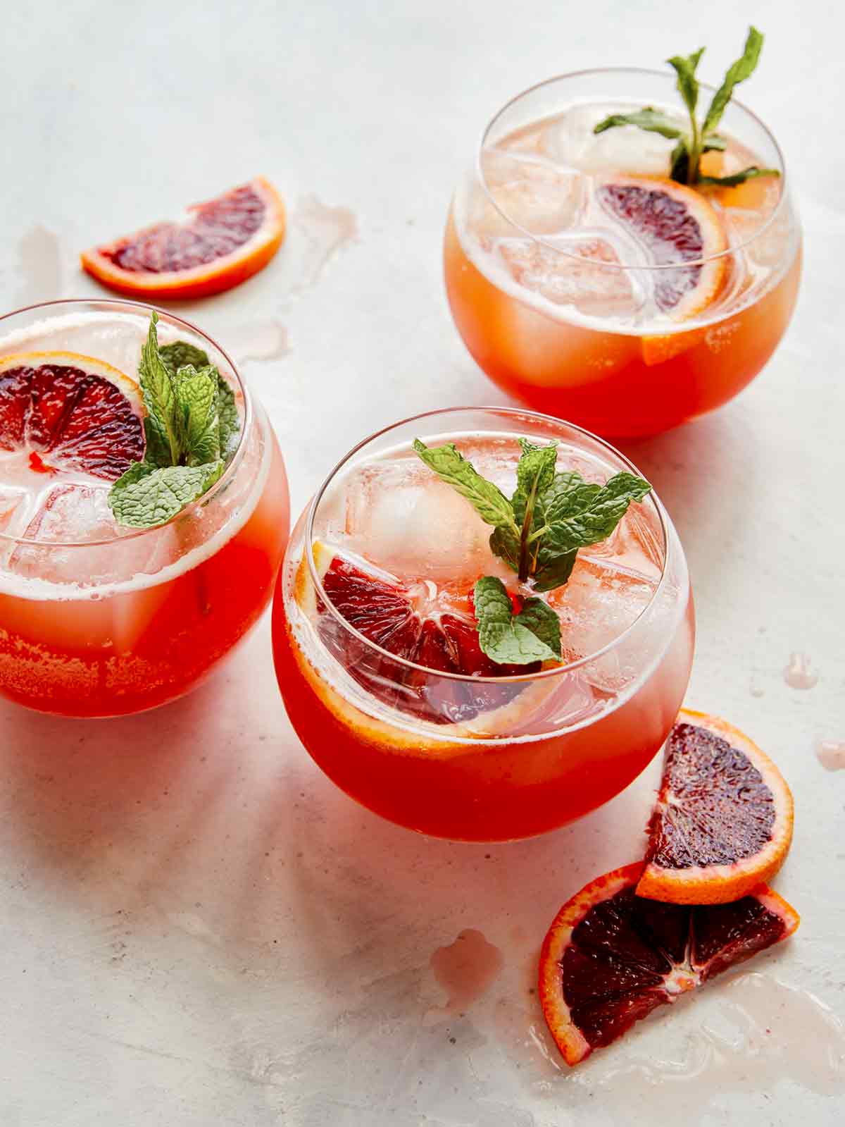 Blood orange shandy cocktails garnished with blood oranges and mint.