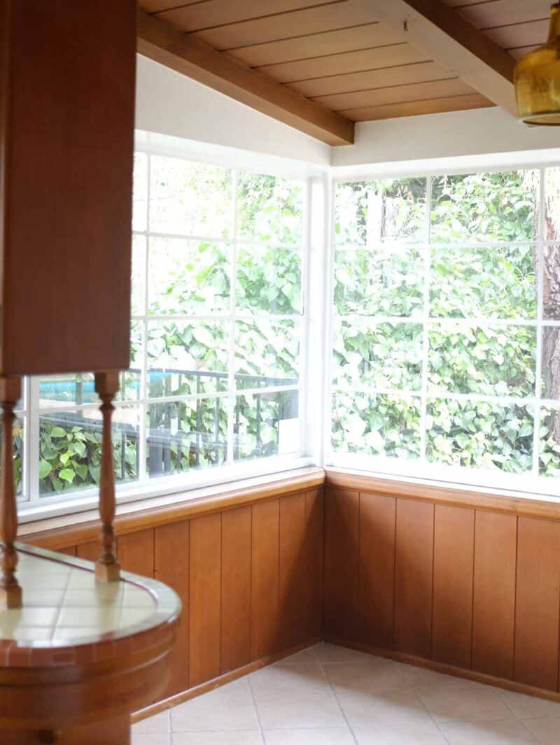 A kitchen breakfast nook with wooden cabinets and windows.