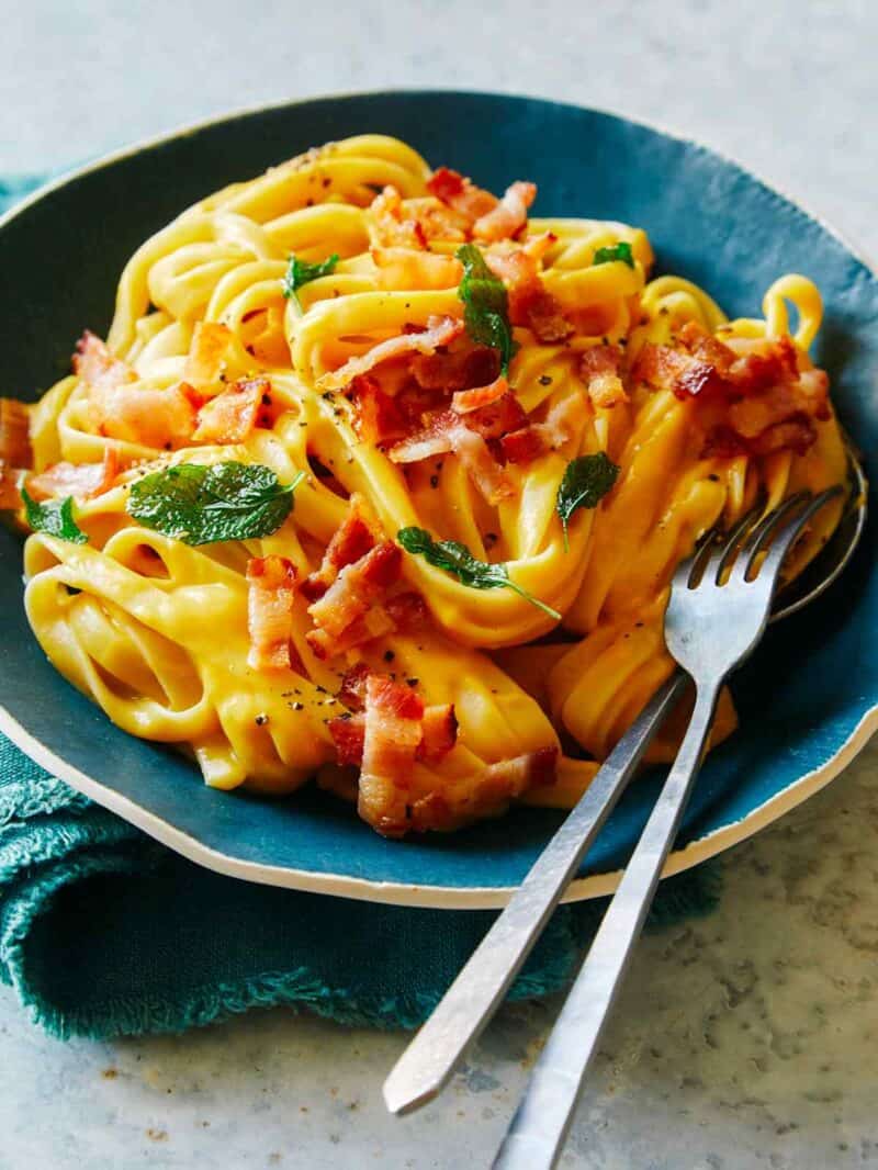 Dairy free creamy butternut squash pasta in a blue bowl with a fork.