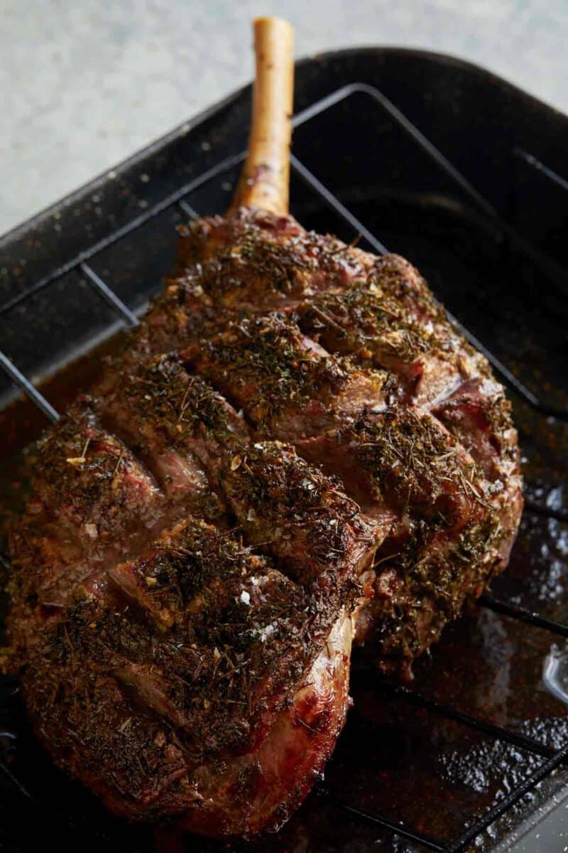 A close up of herb crusted leg of New Zealand grass fed lamb on a grill.