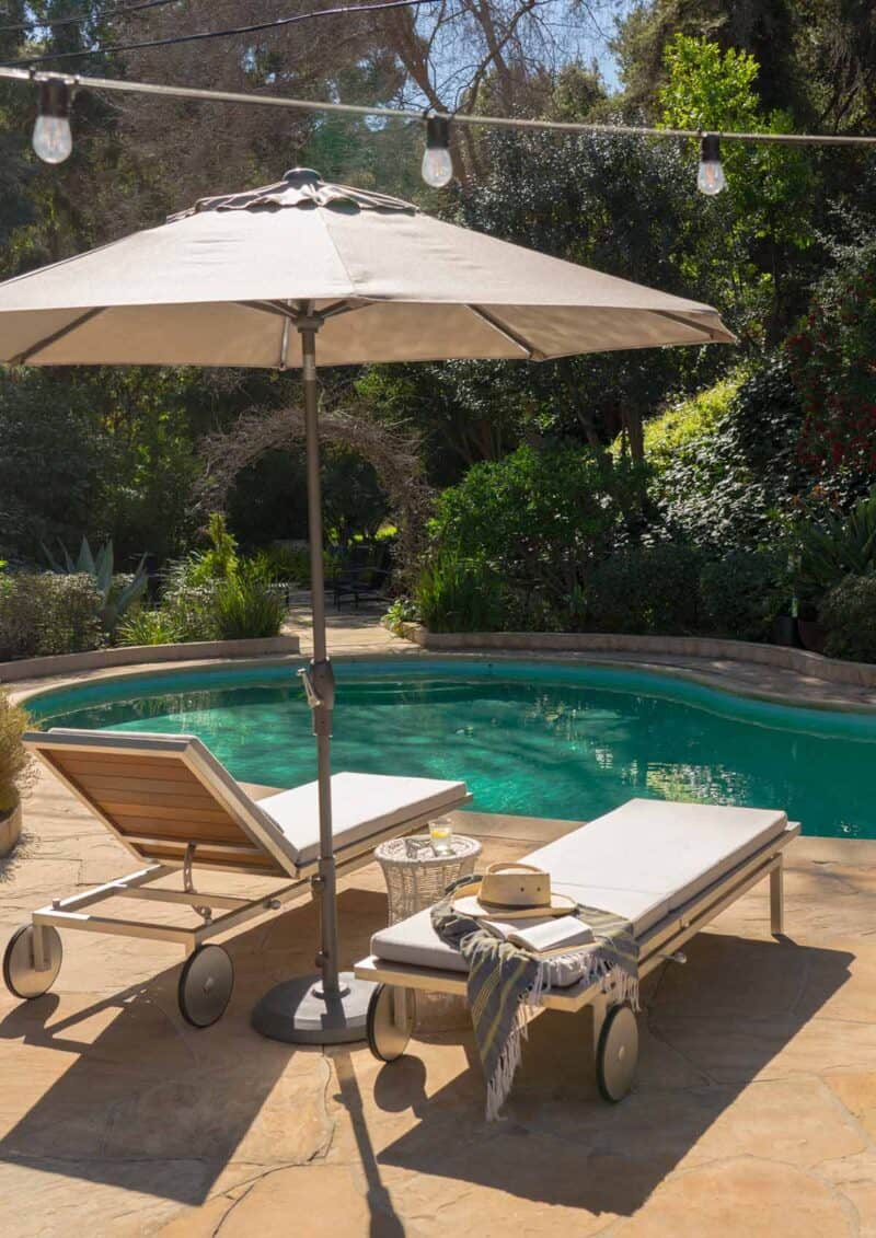 Chaise lounges with umbrella by a pool.