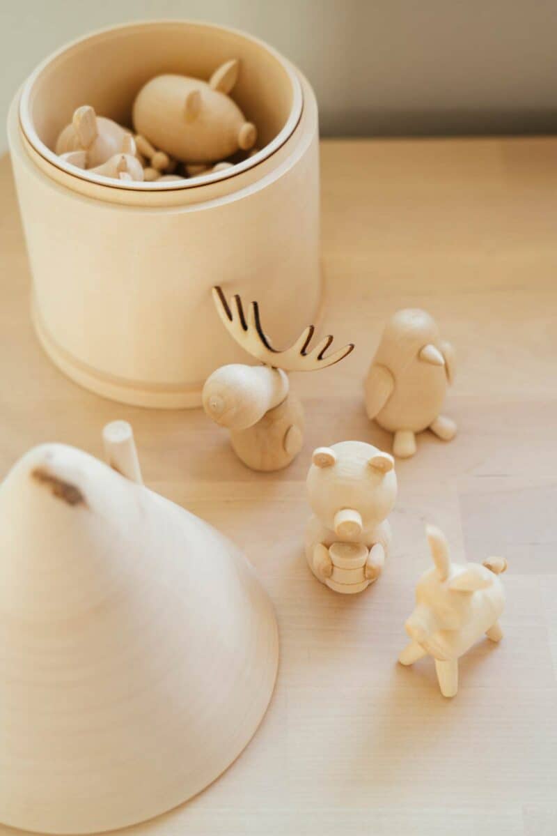 A variety of small wooden animals in and out of container.