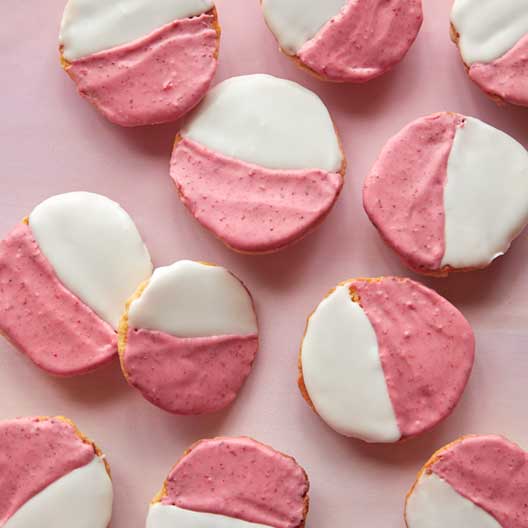 Pink and white cookies on a pink surface. 