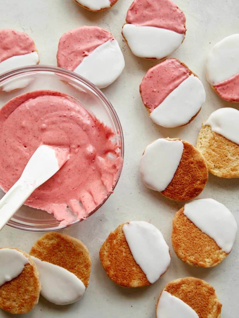 Half frosted pink and white Valentine\'s Day cookies with pink frosting in a bowl.