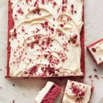 A whole raspberry sheet cake with white chocolate frosting with slices cut off.