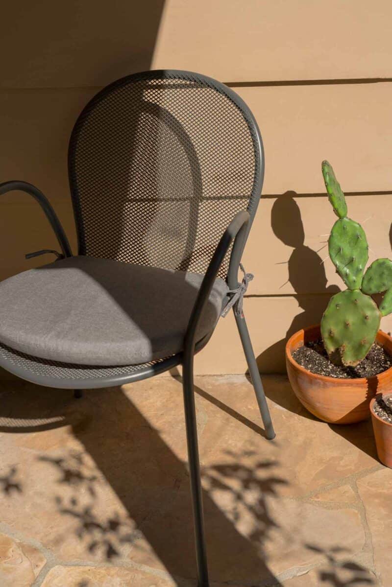 Outdoor chair next to a cactus.