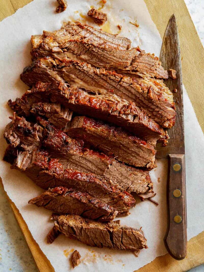 Slow cooked BBQ Wagyu Beef brisket sliced on a cutting board with a knife.