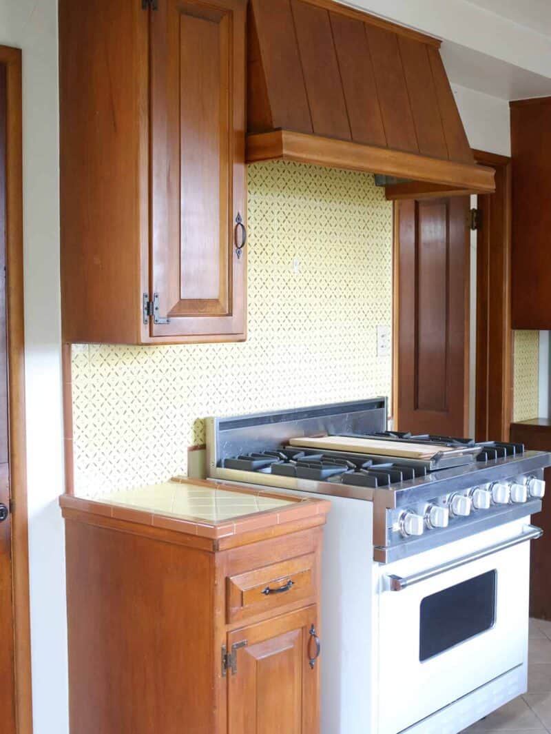 A stove top oven with wooden cabinets.