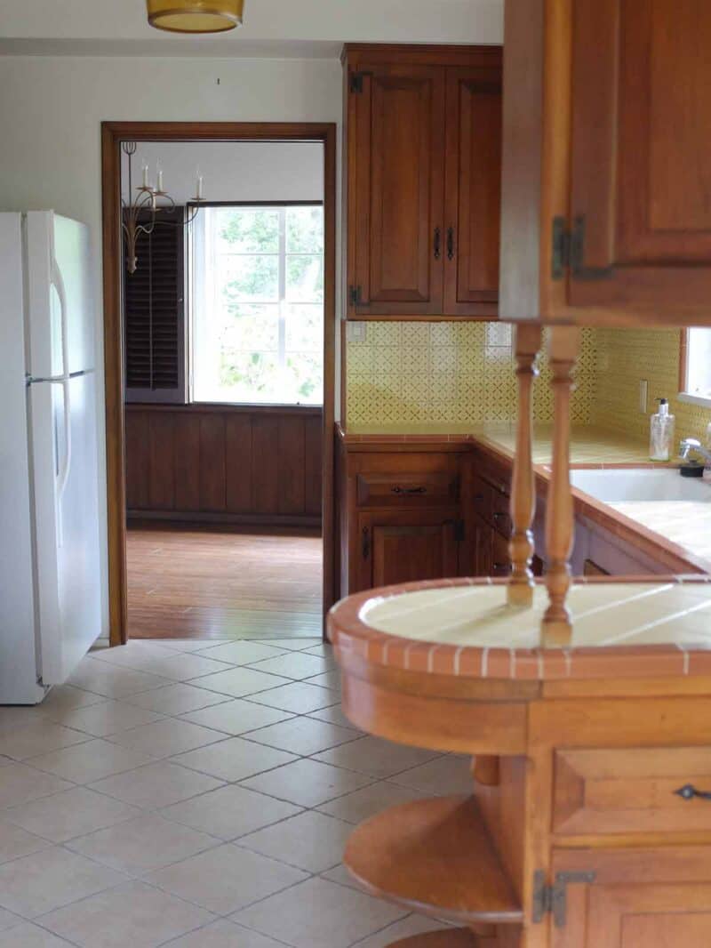 A kitchen with wooden cabinets looking into the dining room.