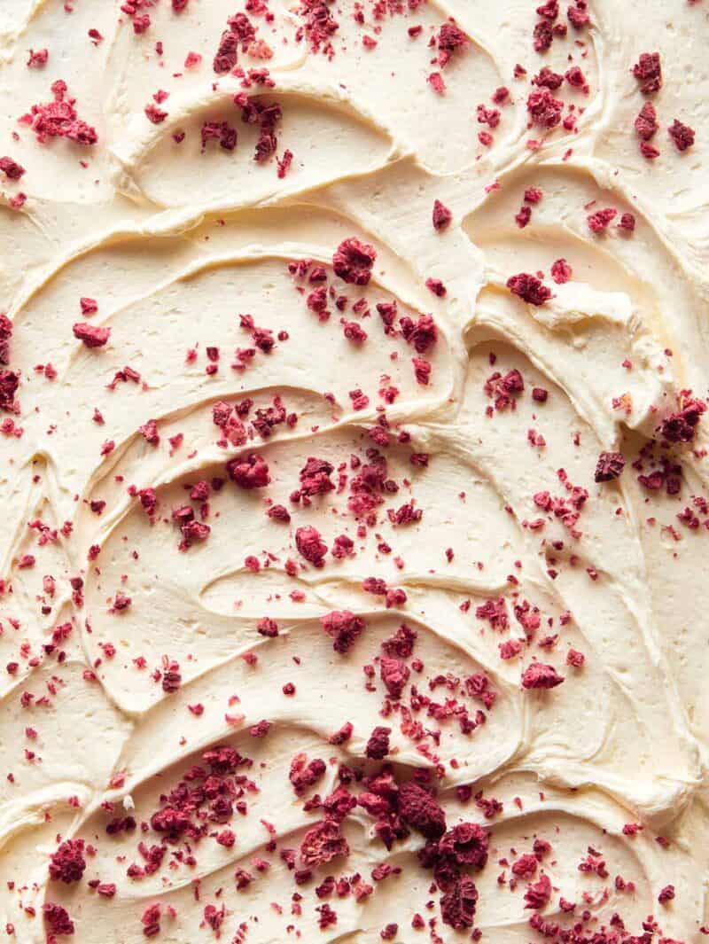 A close up of white chocolate frosting with freeze dried raspberries.