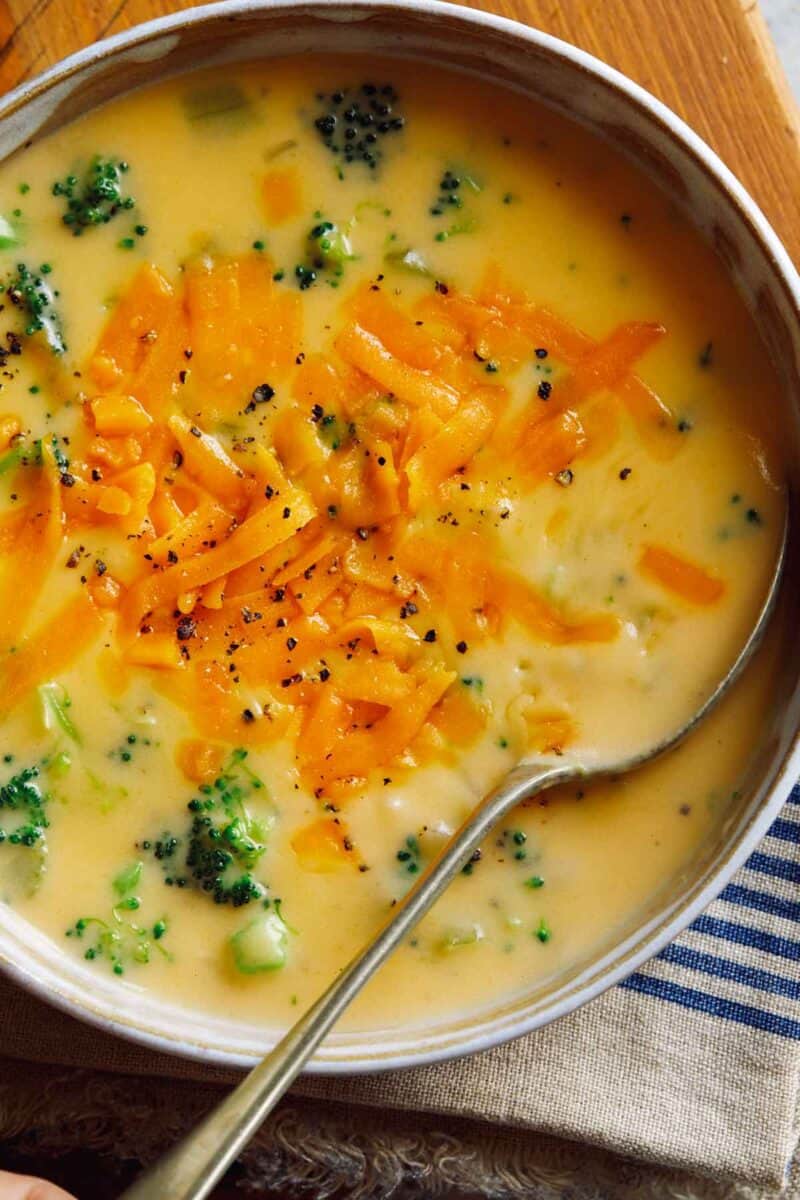 Broccoli cheddar soup in a bowl up close with shredded cheddar cheese on top. 