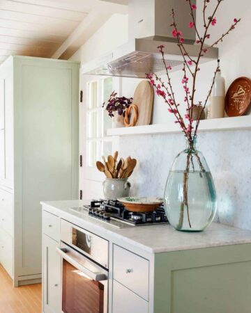 Bosch Stove top oven with wooden spoons and vase on the counters with shelving above.