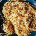 A close up of capellini with garlic lemon and parmesan with a fork.