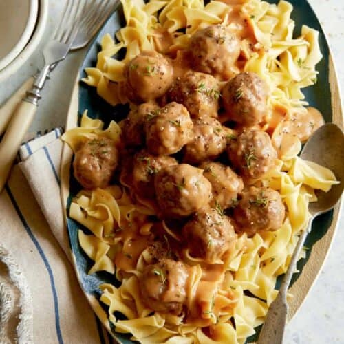 Grass fed lamb meatballs with gravy over egg noodles with forks.