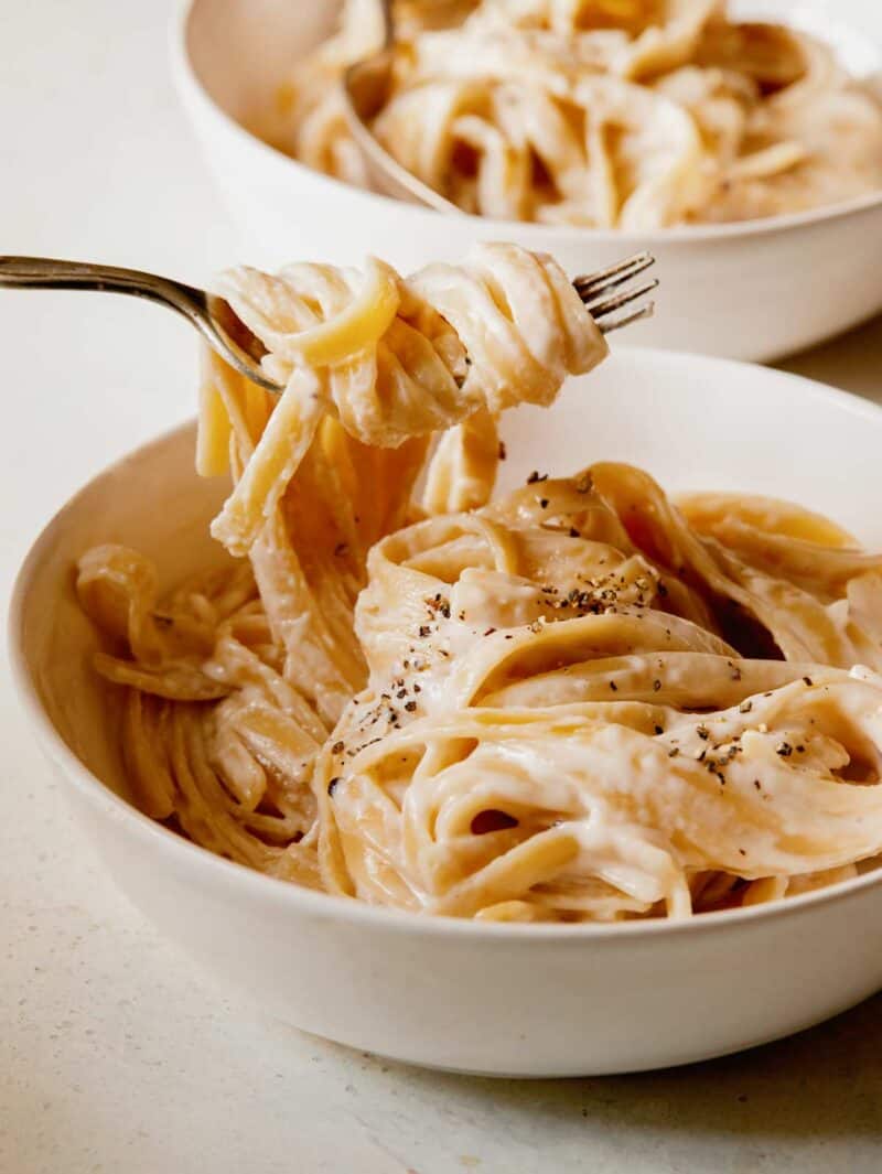 One pot fettuccine alfredo in a bowl with a fork in the pasta. 
