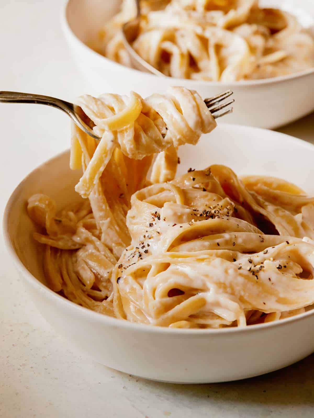 One pot fettuccine alfredo in a bowl with a fork in the pasta.