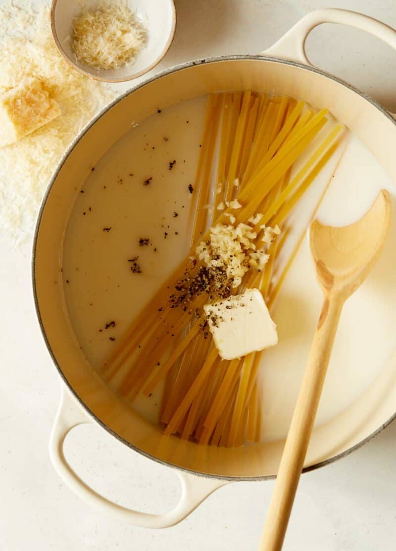 One pot fettuccine alfredo in pot with a wooden spoon.