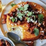 Spiced chicken topped tahchin on a plate served with a spoon.