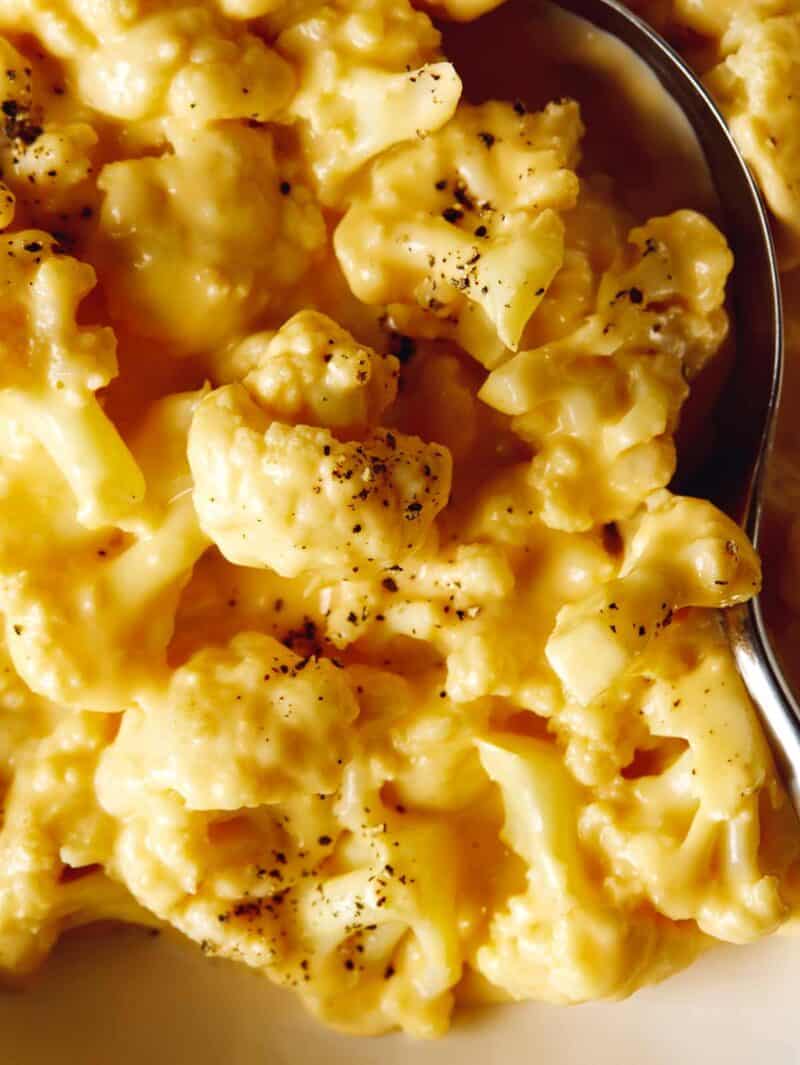 A close up on cauliflower mac and cheese with a spoon in it.