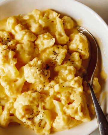 A close up of cauliflower mac and cheese with a spoon.