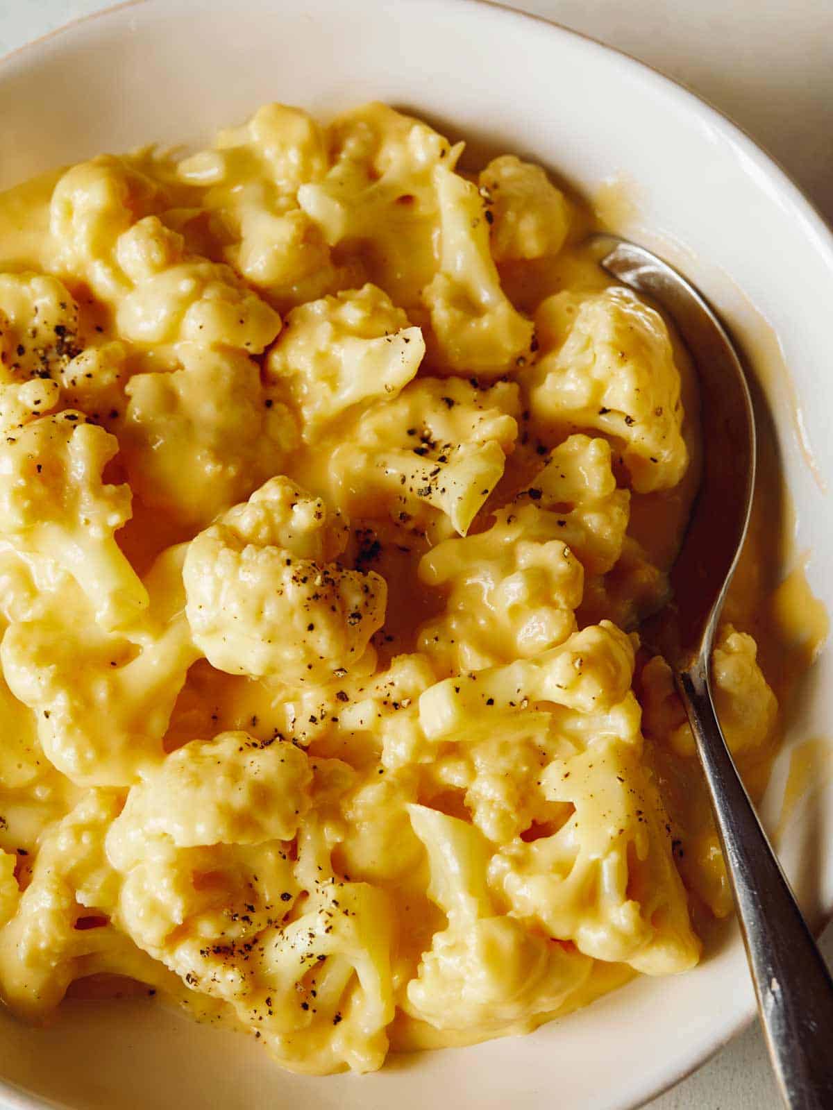 A close up of cauliflower mac and cheese with a spoon.