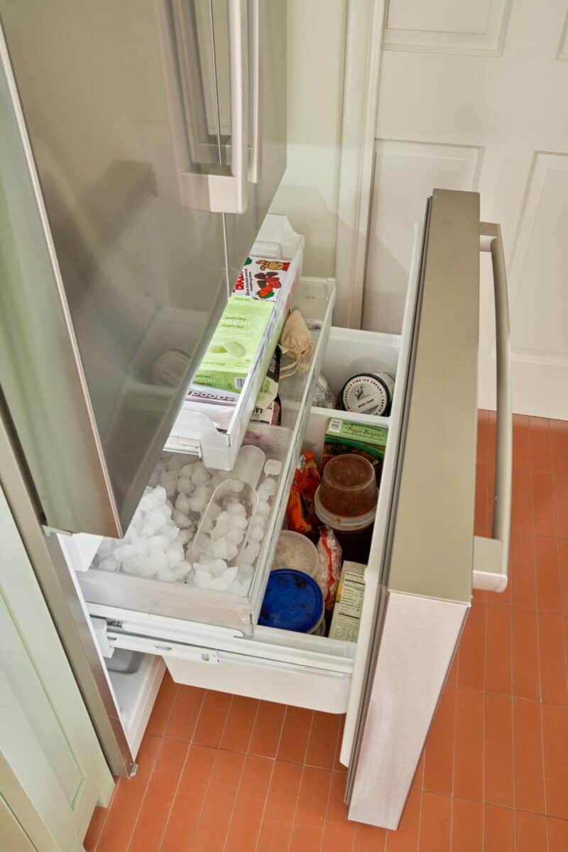 The inside of a freezer drawer with ice and frozen foods.