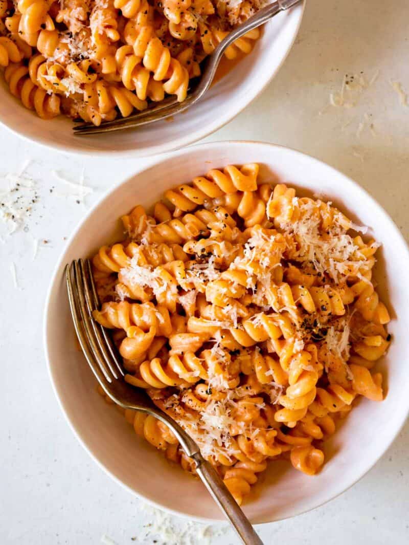 Bowls of fusilli pasta with vodka sauce and forks.