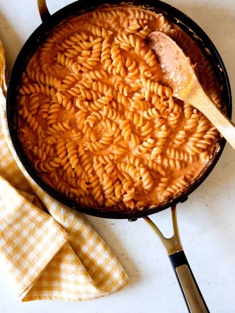 Fusilli pasta with vodka sauce in a skillet with a wooden spoon.