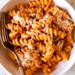 A close up of a bowl of fusilli pasta with vodka sauce and a fork.